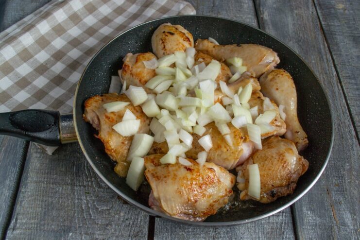 Sautéing Onions with Chicken to Build a Flavorful Base Diced onions being sautéed with golden-brown chicken pieces in a pan.