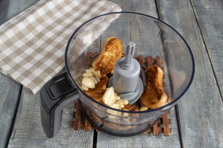 Making the Creamy Nut Sauce Base in a Blender Peanuts, garlic cloves, and pieces of white bread in a blender cup, ready to be mixed.