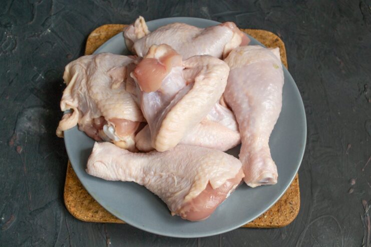 Raw chicken pieces on a cutting board, prepared for making Chakhokhbili stew.