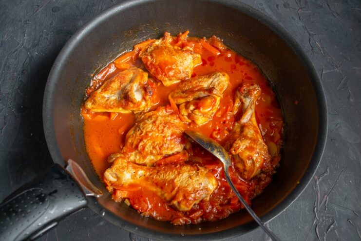 A covered skillet simmering on the stove, cooking the Chakhokhbili stew.