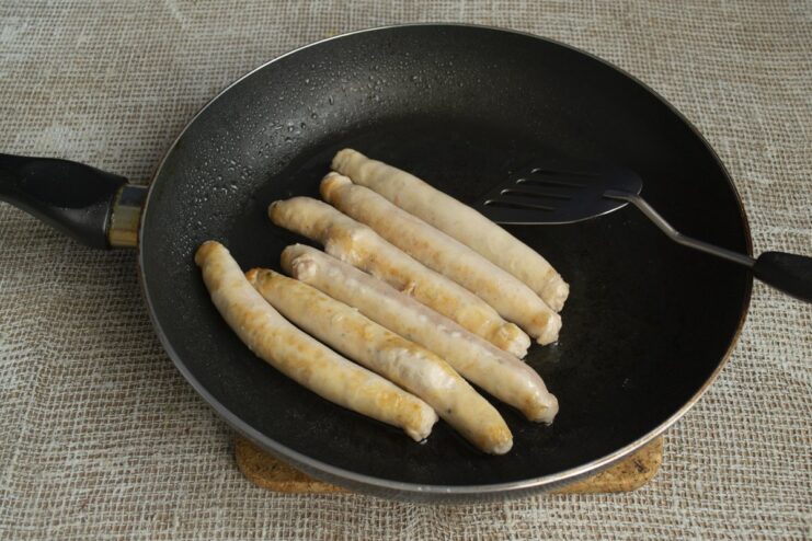 Step 1: Browning the chicken sausages to lock in flavor Chicken sausages being fried in a pan until golden brown.