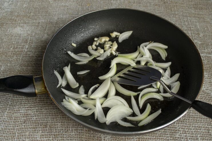 Building the flavor base with garlic and onions Sliced onions and minced garlic being sautéed in a pan.