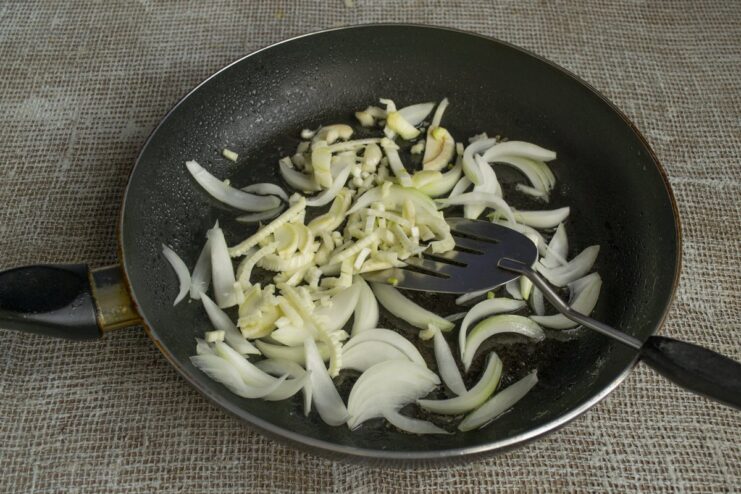 Adding finely chopped fennel for a hint of anise flavor Finely chopped fennel being added to the sautéed onions and garlic in the pan.