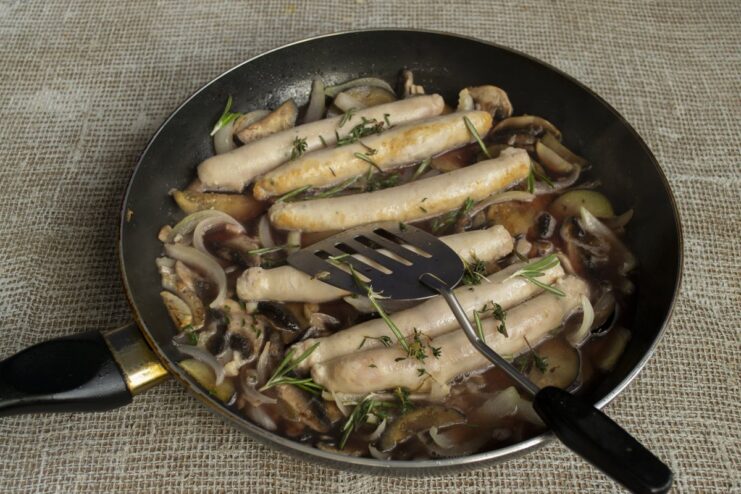 Combining sausages and herbs to meld the flavors Cooked sausages returned to the pan with vegetables and fresh thyme and rosemary.