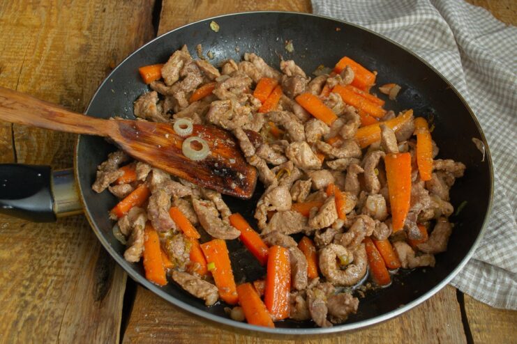 Meat and vegetables being cooked together in a skillet.