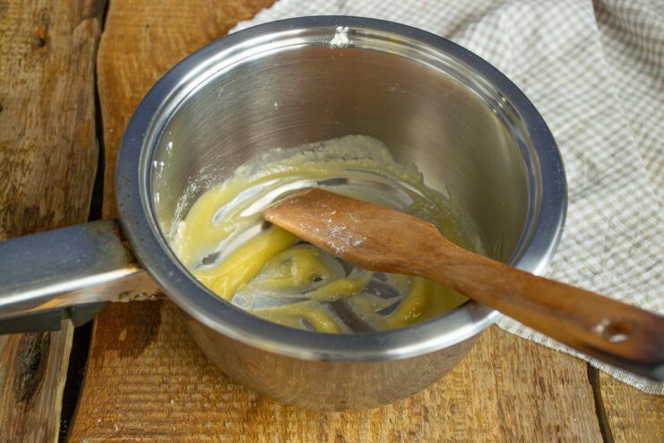 Making a roux by cooking flour in melted butter in a saucepan.