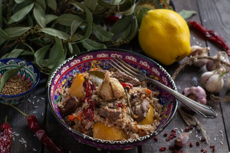 A large platter of freshly cooked plov with quince and beef, ready to be served.