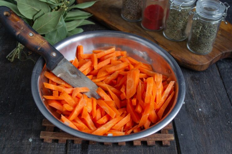 Cutting Carrots into Julienne Strips for Authentic Plov Carrots being cut into thick sticks (julienne) on a cutting board.