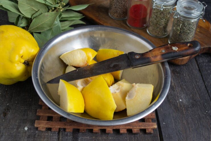 Preparing Quince for Plov A quince being cut into large chunks on a cutting board, with the core removed.