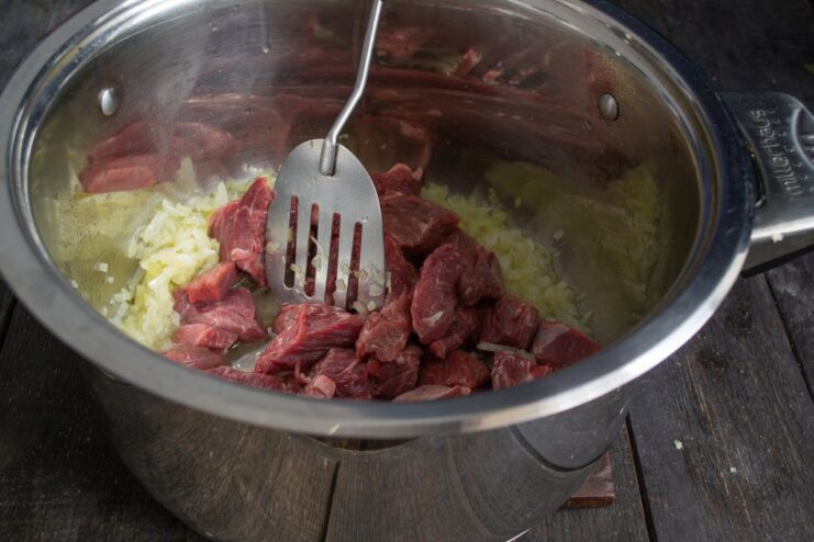 Sautéing Onions and Beef for the Plov Base Beef and onions being fried in a large pot or kazan.