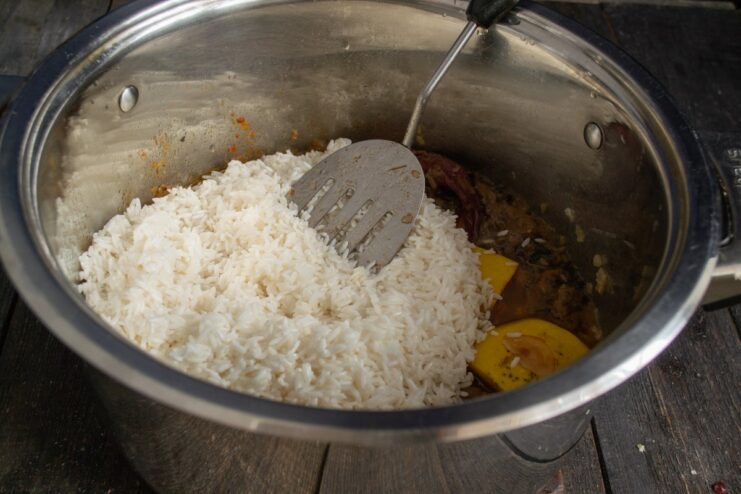 Layering Rice and Adding Garlic for Steaming A layer of rice covering the meat and quince, with a whole head of garlic in the center.
