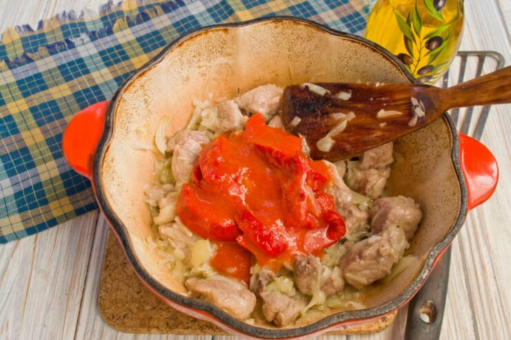 Meat and onions simmering in a rich tomato sauce in a pot.
