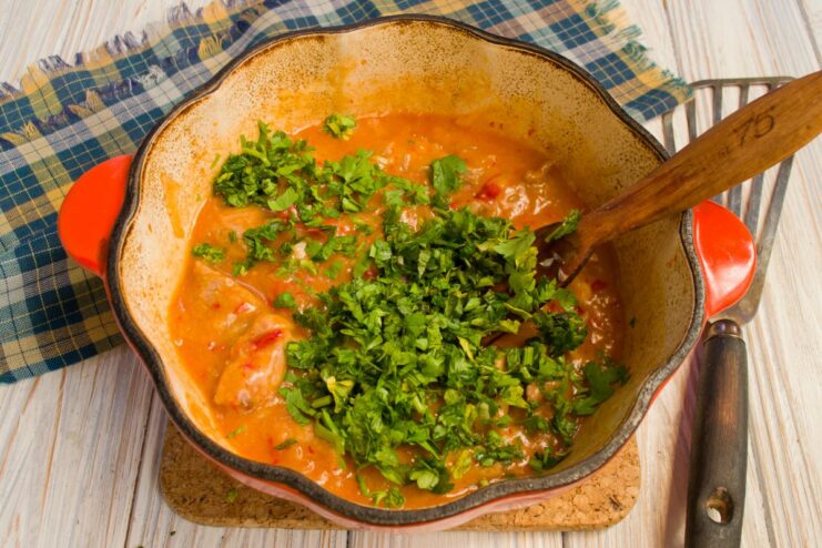 Freshly chopped cilantro being added to the meat stew in the pot.
