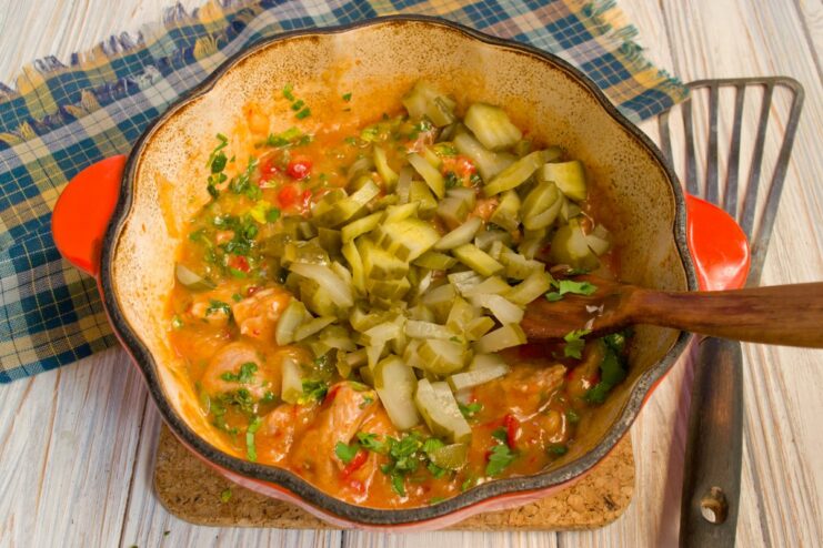 Julienned pickles being added to the simmering meat stew.