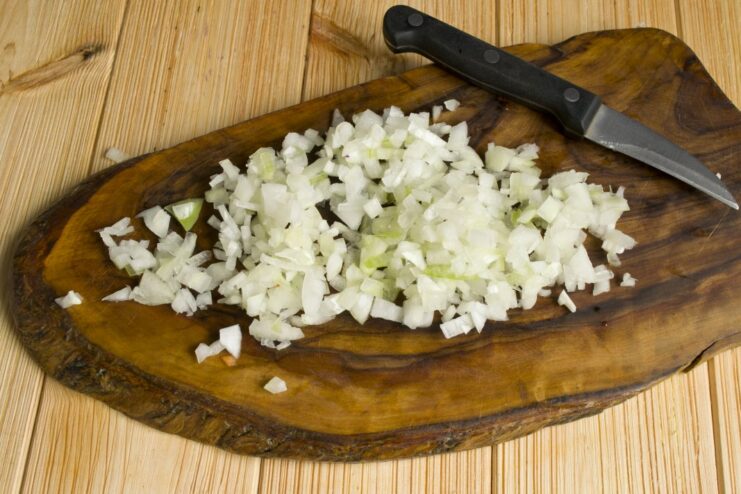 Sautéing Onions Until Golden for a Flavorful Base Chopped onions being sautéed in a frying pan with a wooden spatula.