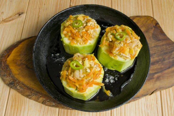 Arranging Stuffed Zucchini in a Pan Before Baking Hollowed zucchini rounds filled with stuffing, arranged in an oven-safe pan.