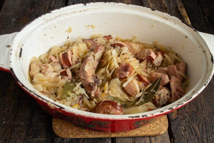Simmering the Bigos stew slowly to meld all the flavors together. A covered Dutch oven simmering on the stove, cooking the Bigos.