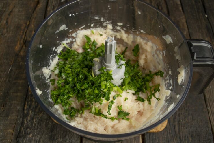 Adding Fresh Herbs to the Ground Chicken Mixture Freshly chopped parsley being added to a bowl of ground chicken for meatballs.