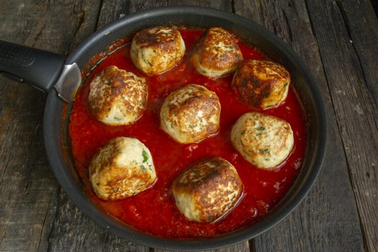 Finishing the Dish: Simmering Meatballs in Tomato Sauce Finished chicken meatballs simmering in a pan with rich tomato sauce, ready to be served.