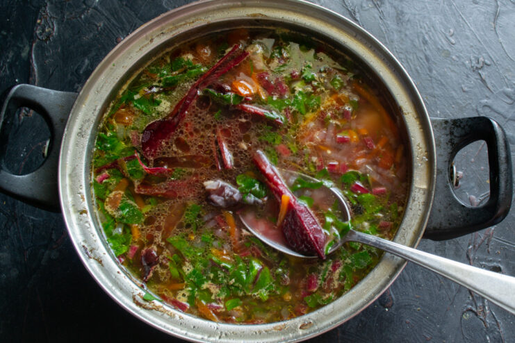 Cooked young beets being added to the pot of finished borscht.