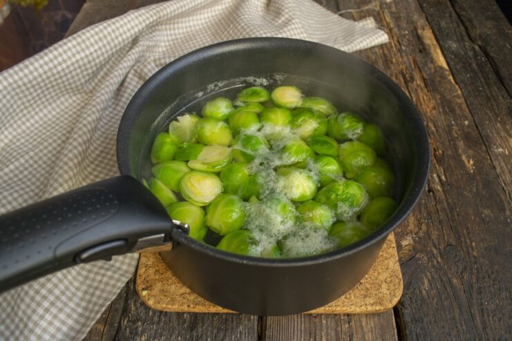 Cooking Brussels sprouts until tender-crisp. Brussels sprouts boiling in a pot of water on the stove.