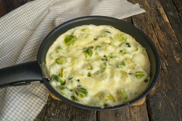 The final dish: perfectly baked Brussels sprouts with a golden cheese crust. A close-up of the finished baked Brussels sprouts in a creamy, cheesy sauce.