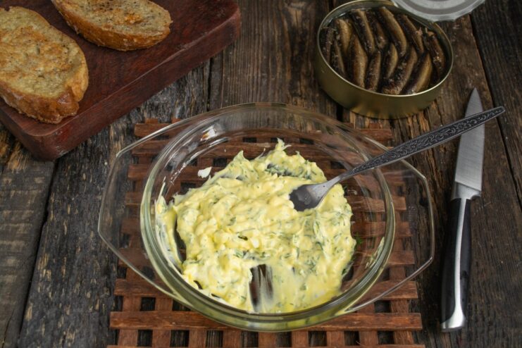 Mashing the Ingredients into a Paste A fork mashing egg, cheese, and herbs into a thick paste in a bowl.