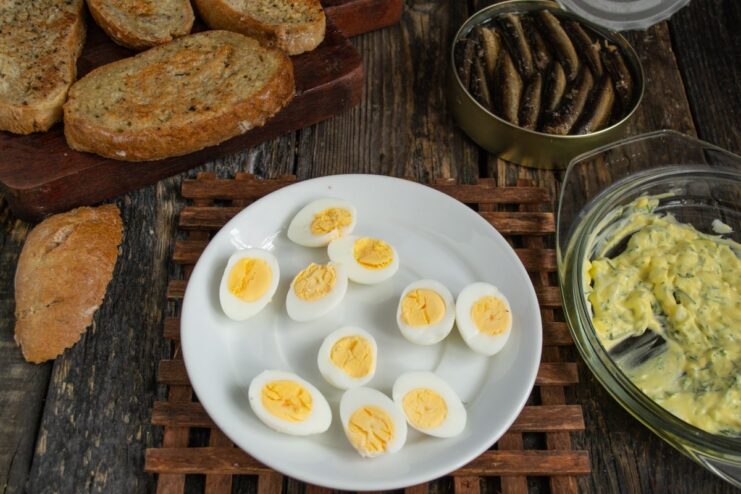 Halving the Boiled Quail Eggs for Garnish Hard-boiled quail eggs being cut in half on a wooden board.