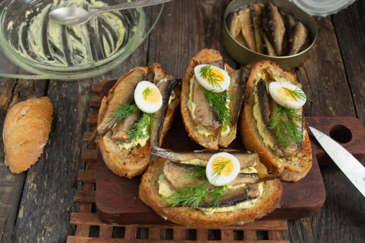 Garnishing the Sprat Sandwiches Garnishing the sprat sandwiches with halved quail eggs and dill sprigs.