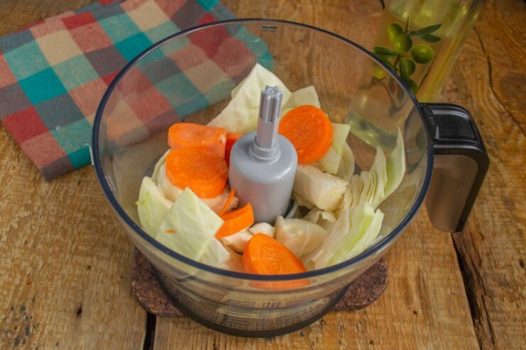 Adding Carrots for Color and Sweetness Chopped carrots added to the cabbage in the blender bowl.