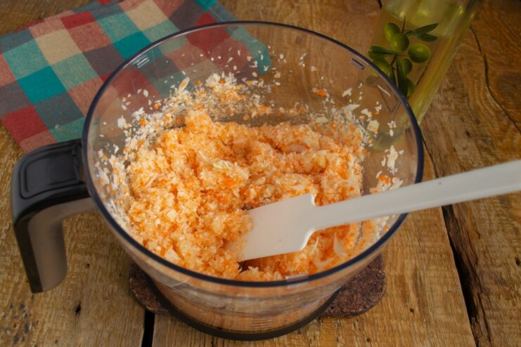 Pulsing Vegetables in a Blender until Finely Chopped A blender filled with finely chopped cabbage, carrots, and onions.