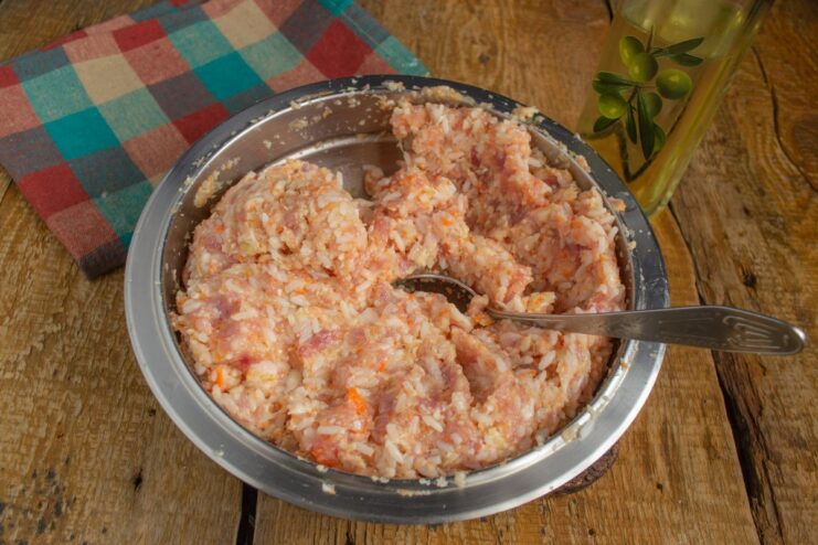Mixing the Ingredients for Lazy Golubtsy Thoroughly A hand mixing ground meat, rice, and vegetables in a bowl to make the lazy golubtsy mixture.