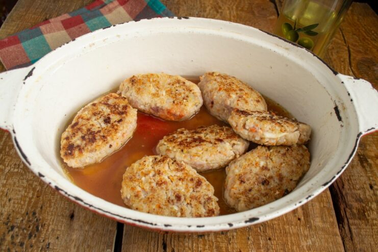 Layering the Rolls and Adding Tomato Broth for Stewing Layers of lazy golubtsy in a pot with a tomato broth being poured over them.