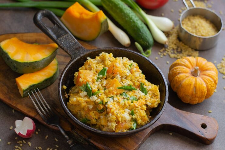 A serving of quick bulgur with pumpkin in a white bowl, garnished with fresh herbs.