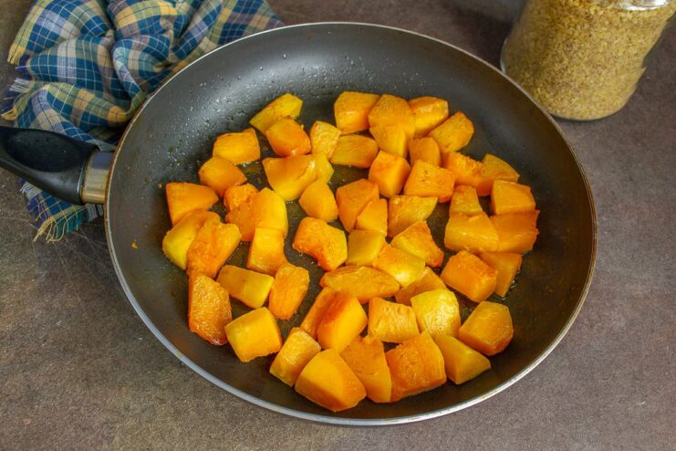 Frying pumpkin cubes until golden brown Cubes of pumpkin being sautéed in a skillet until golden.