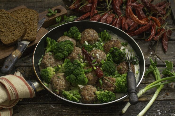A serving of quick meat patties and broccoli florets in a creamy white béchamel sauce in a pan.