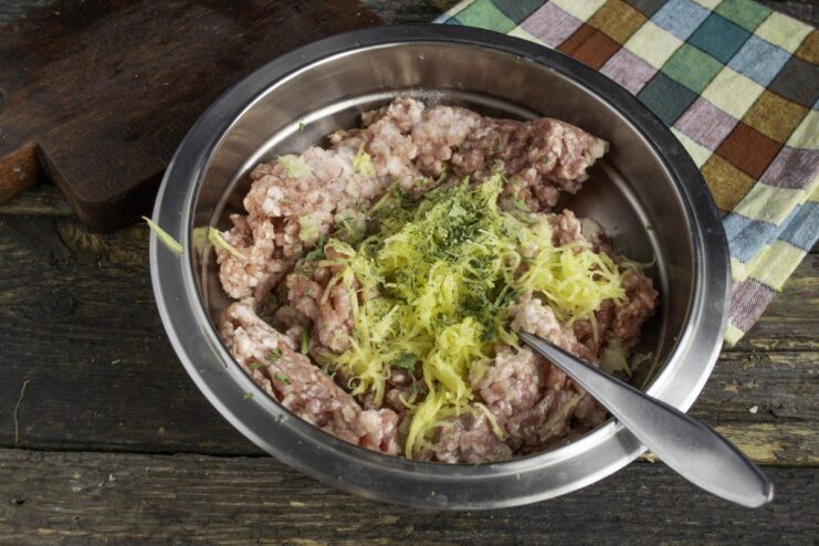 Seasoning the Meat Mixture with Parsley and Salt Dried parsley and salt being sprinkled into the bowl with ground meat.