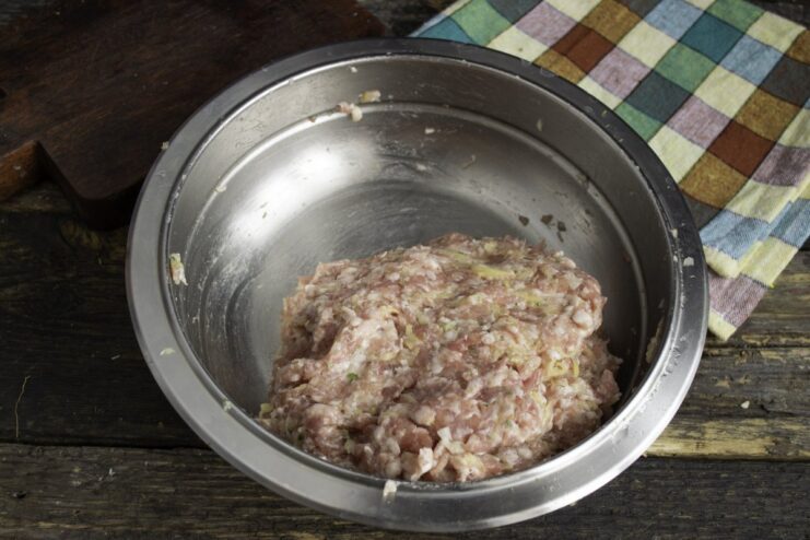 Kneading the Ground Meat Mixture by Hand Hands mixing the ground meat, onion, and potato in a bowl to combine.