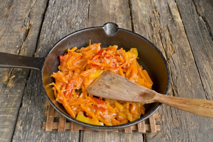 Sautéing Vegetables in a Skillet Until Tender and Fragrant A mix of chopped onions, carrots, and bell peppers sautéing in a skillet.