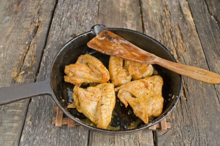 Frying Chicken Wings Until They Are Perfectly Golden Brown and Crispy Chicken wings being fried in a hot skillet until they reach a golden-brown color.