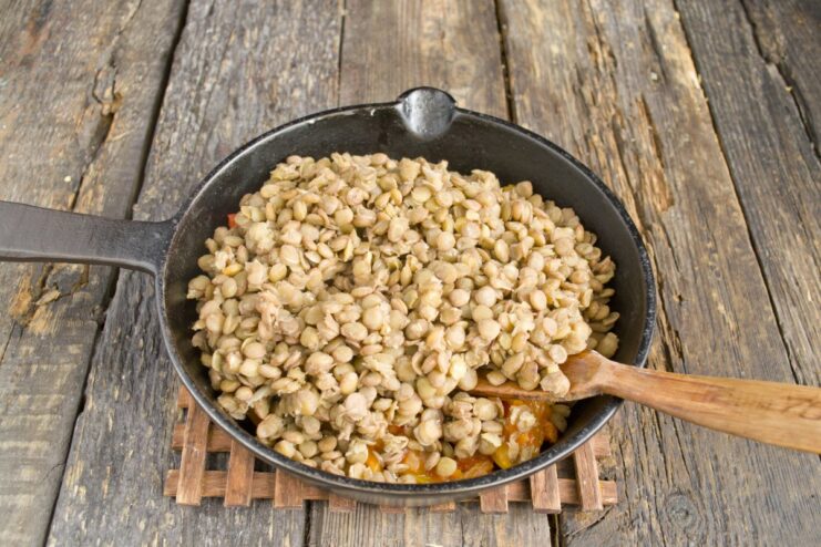Combining the Cooked Lentils with the Sautéed Vegetable Base Adding cooked lentils to a skillet containing a sautéed vegetable mixture.