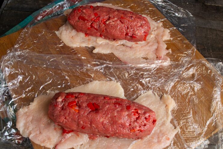 Shaping the Filling for the Roll A log of seasoned meat mince placed on top of the pounded chicken fillet layer.