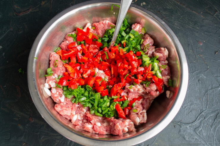 Incorporating Diced Bell Pepper for Flavor and Color Adding diced red bell pepper to the ground meat mixture for sausages.
