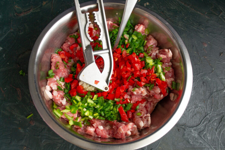 Seasoning the Sausage Meat with Garlic and Chili Adding minced garlic and chopped hot pepper to the sausage mixture.