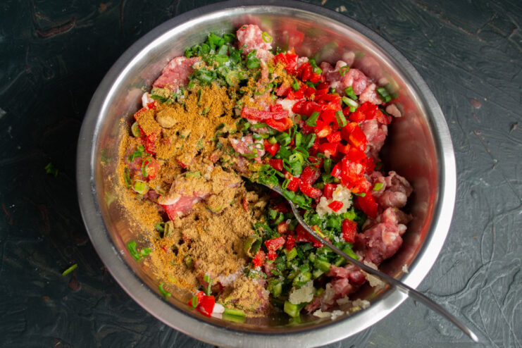 Using Mineral Water to Make Sausages Juicier Pouring sparkling mineral water into the bowl with seasoned ground meat.