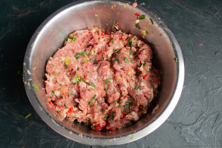 Kneading the Sausage Mixture for the Perfect Texture Kneading the ground meat mixture in a bowl to combine all ingredients.
