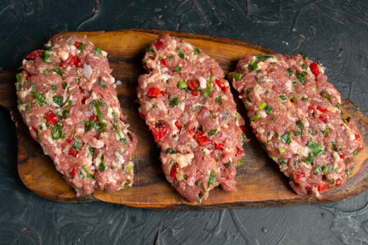 Portioning the Sausage Mixture Before Shaping The ground meat mixture divided into four equal portions on a cutting board.