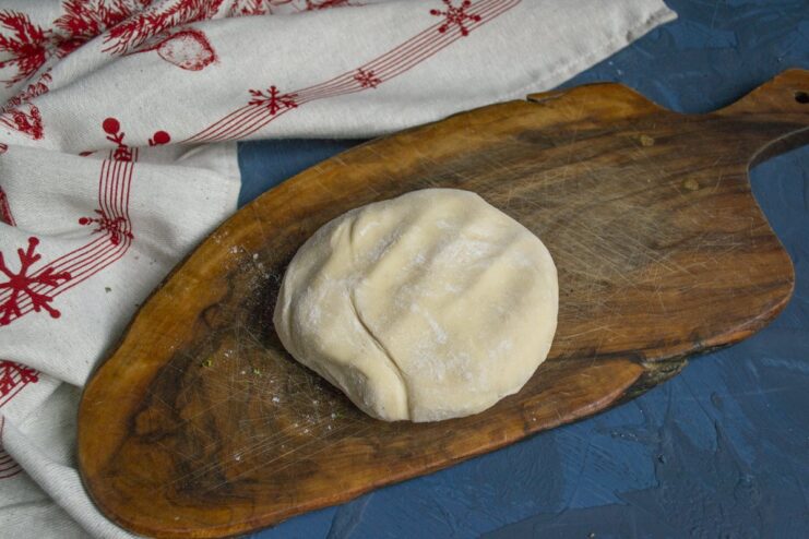 How to Make Perfect Dough for Pelmeni A ball of smooth, elastic dough for pelmeni on a wooden surface.