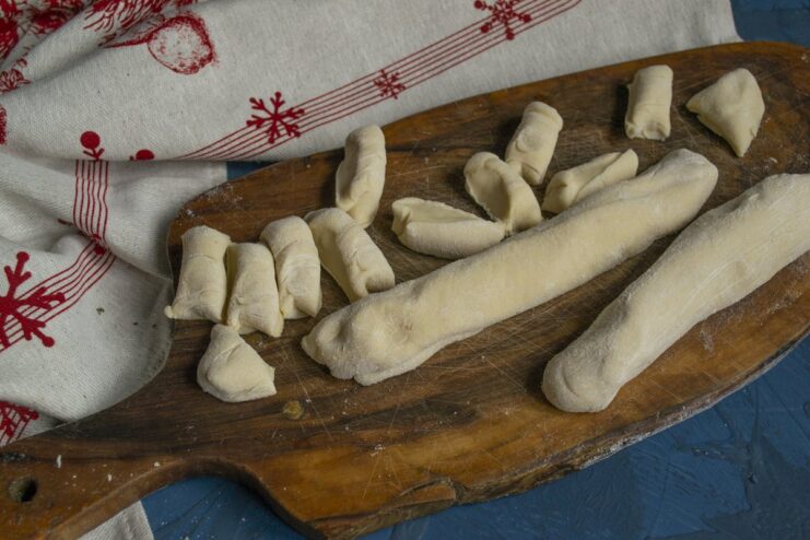 Portioning the Dough for Individual Dumplings Pelmeni dough rolled into a log and sliced into small, even pieces.