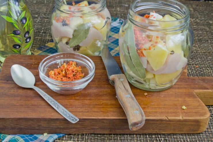 Final Seasonings: Adding Dried Carrots and Salt Dried carrots and salt being sprinkled into the jars over the other ingredients.